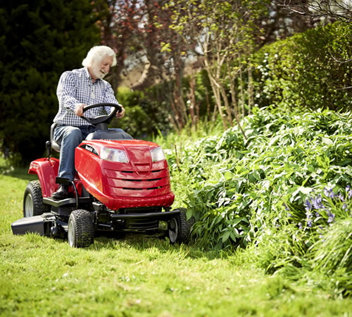 Older man riding red riding lawn mower