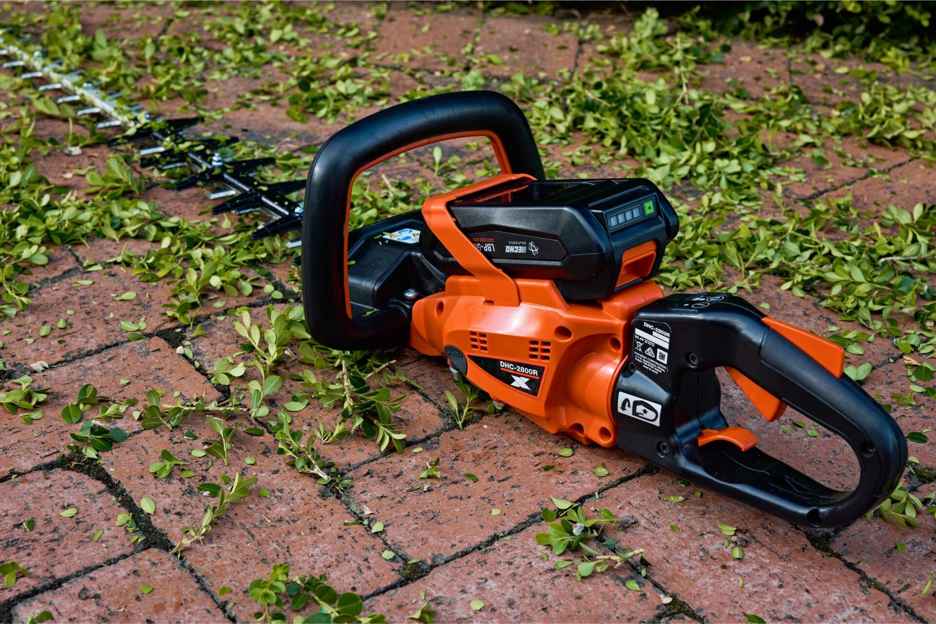 15dzpfs0rjl.jpg - Mowers Online Orange and black chainsaw on brick patio