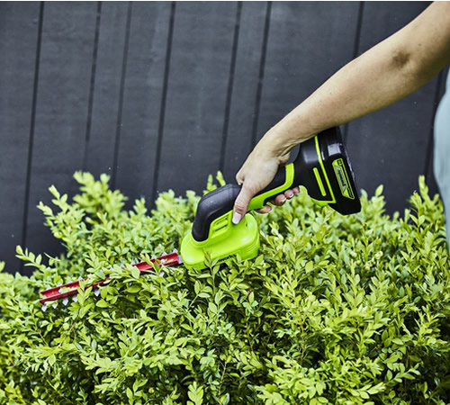 1g0tsfsly3p.jpg - Mowers Online Hand-held cordless hedge trimmer on shrub.