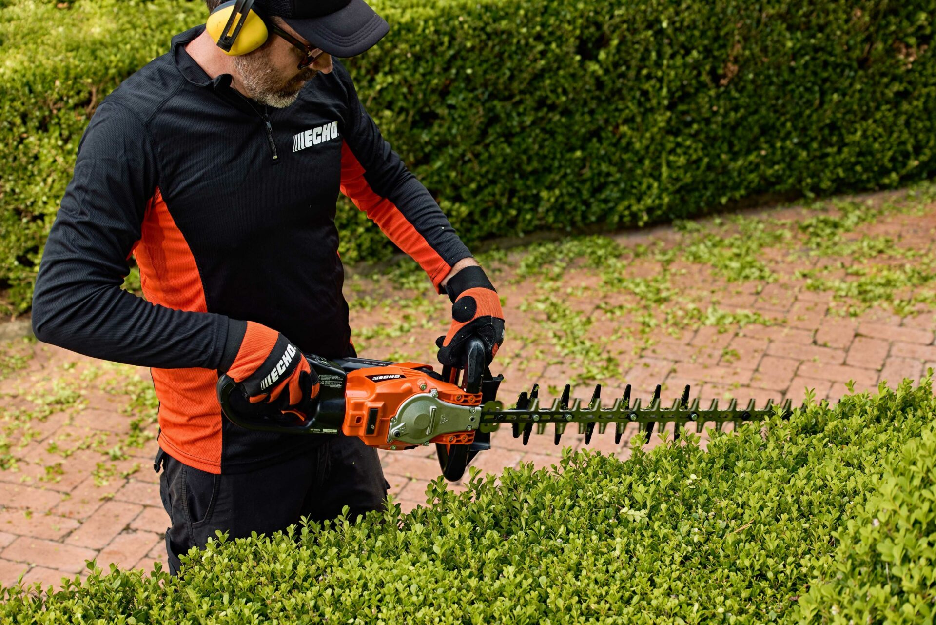 5xbibcq34g4.jpg - Mowers Online Worker using electric hedge trimmer on shrub