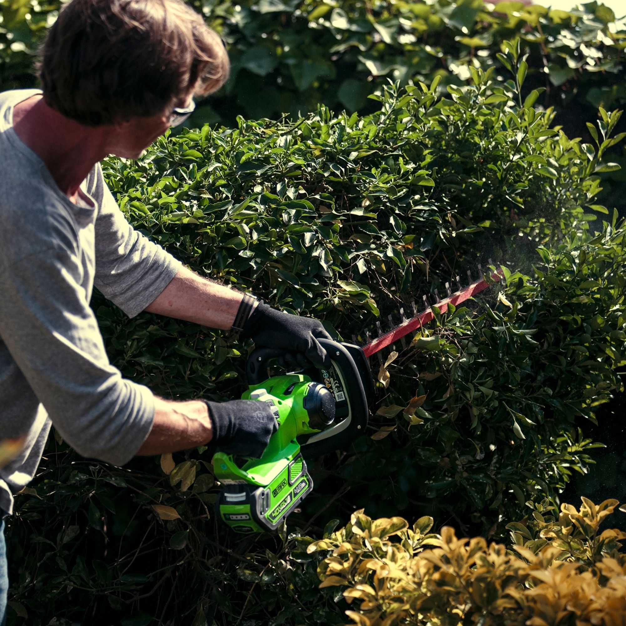 bihl5woyiti.jpg - Mowers Online Man using electric hedge trimmer on shrub