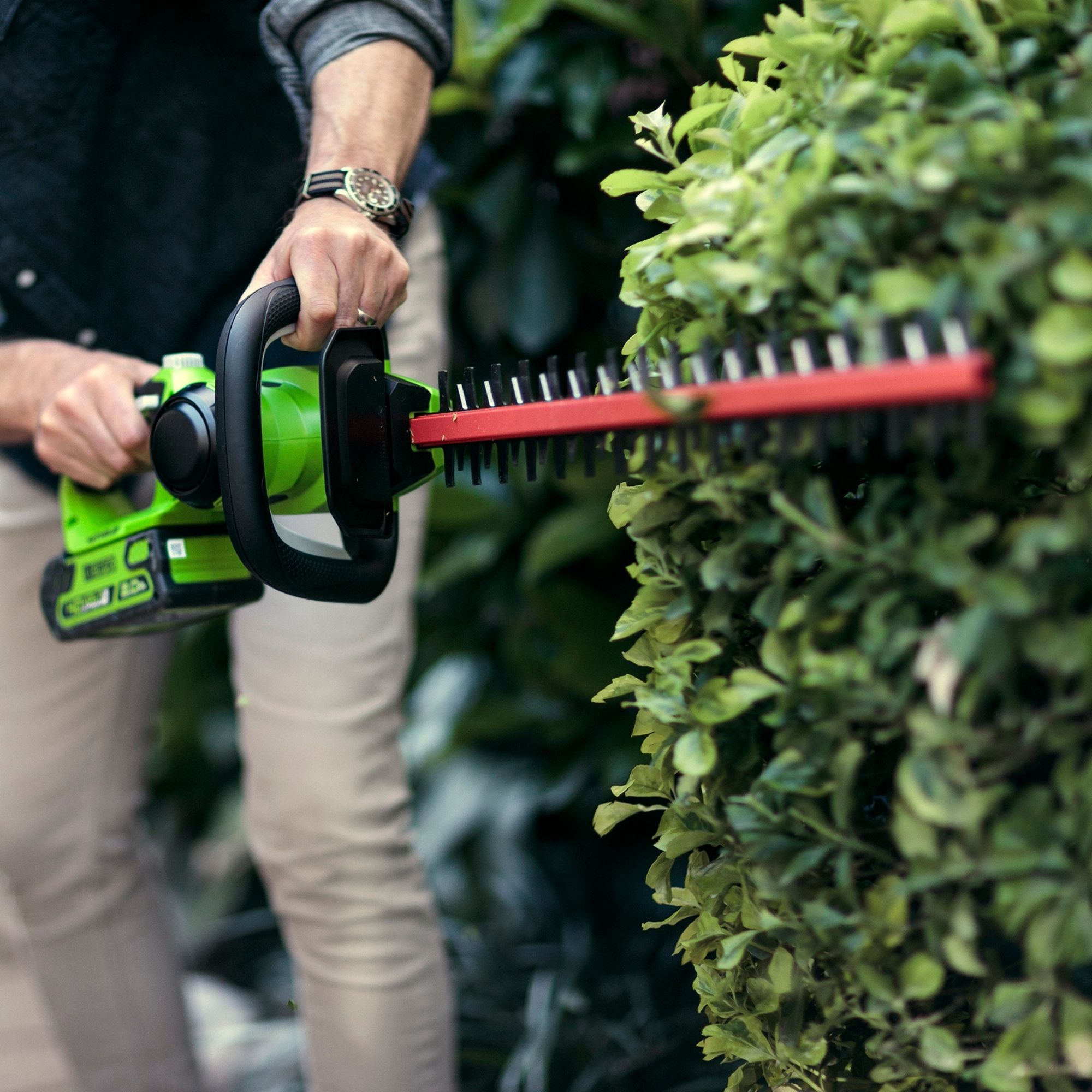hw2urhxipjf.jpg - Mowers Online Person using electric hedge trimmer on shrub