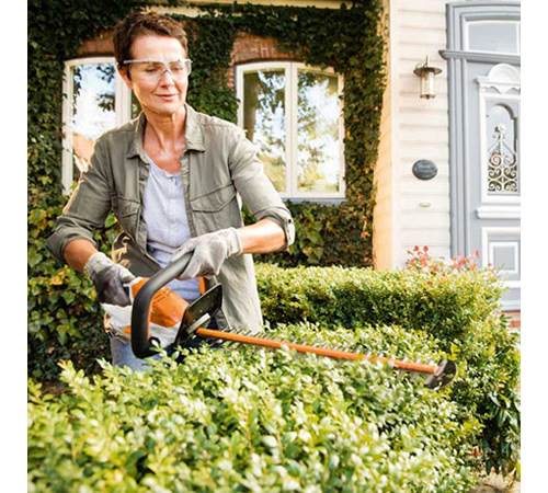 if03tqmxns5.jpg - Mowers Online Woman trimming hedges with electric hedge trimmer