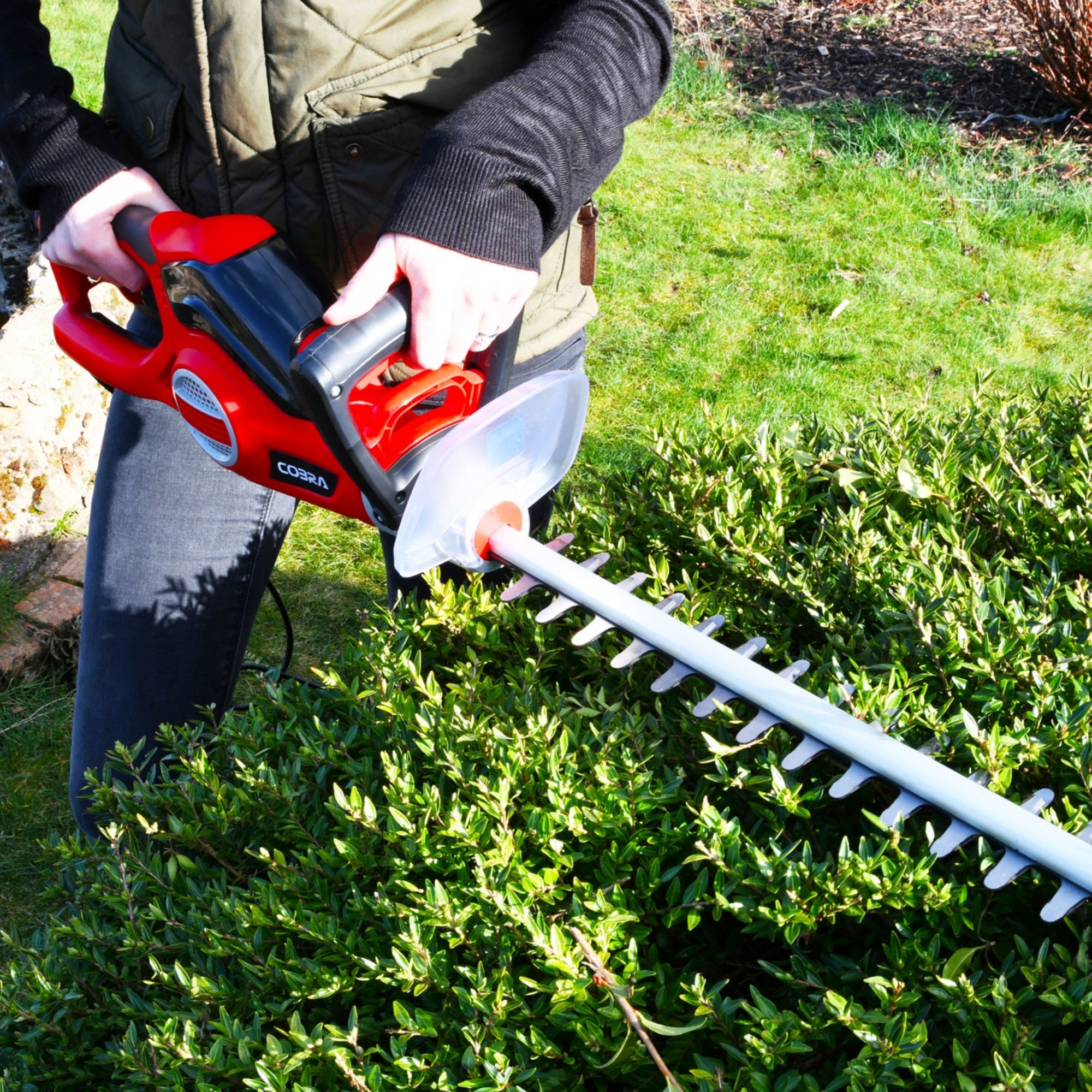 kvc0gko0krs.jpg - Mowers Online Electric hedge trimmer held by person on grass