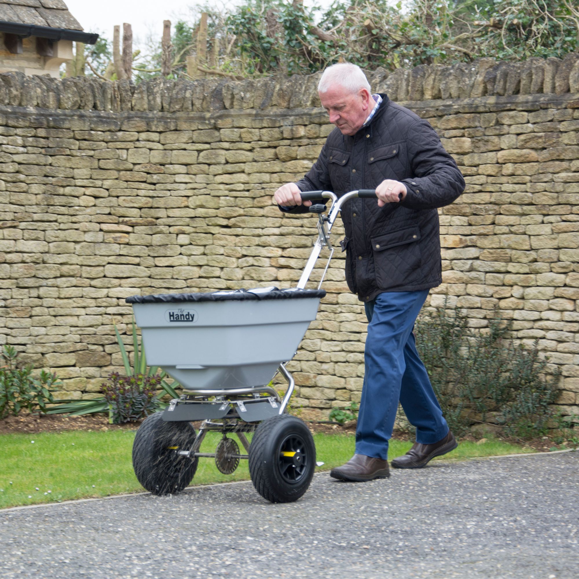 lacw1zc3vdu.jpg - Mowers Online Man pushing garden fertilizer spreader