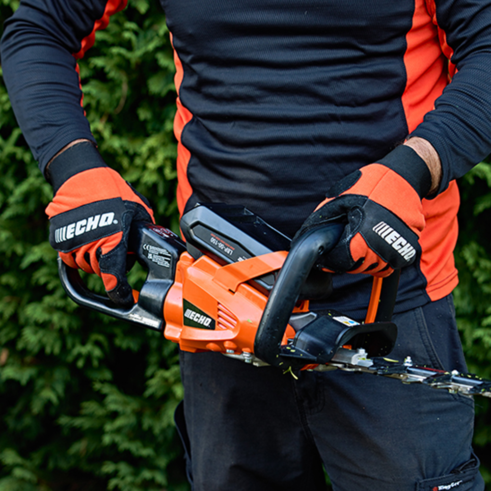 ltzuq11r0ms.png - Mowers Online Person holding Echo chainsaw with orange accents