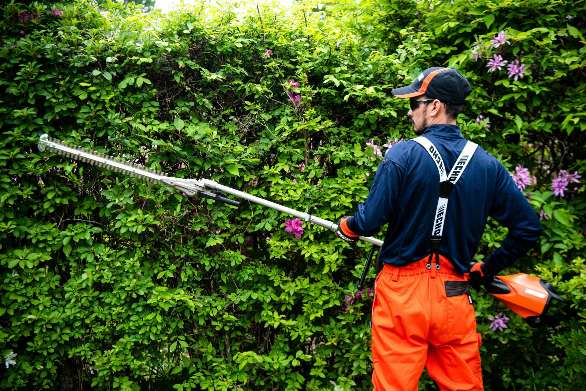 nv45xc3oe4q.jpg - Mowers Online Worker using hedge trimmer on green shrub