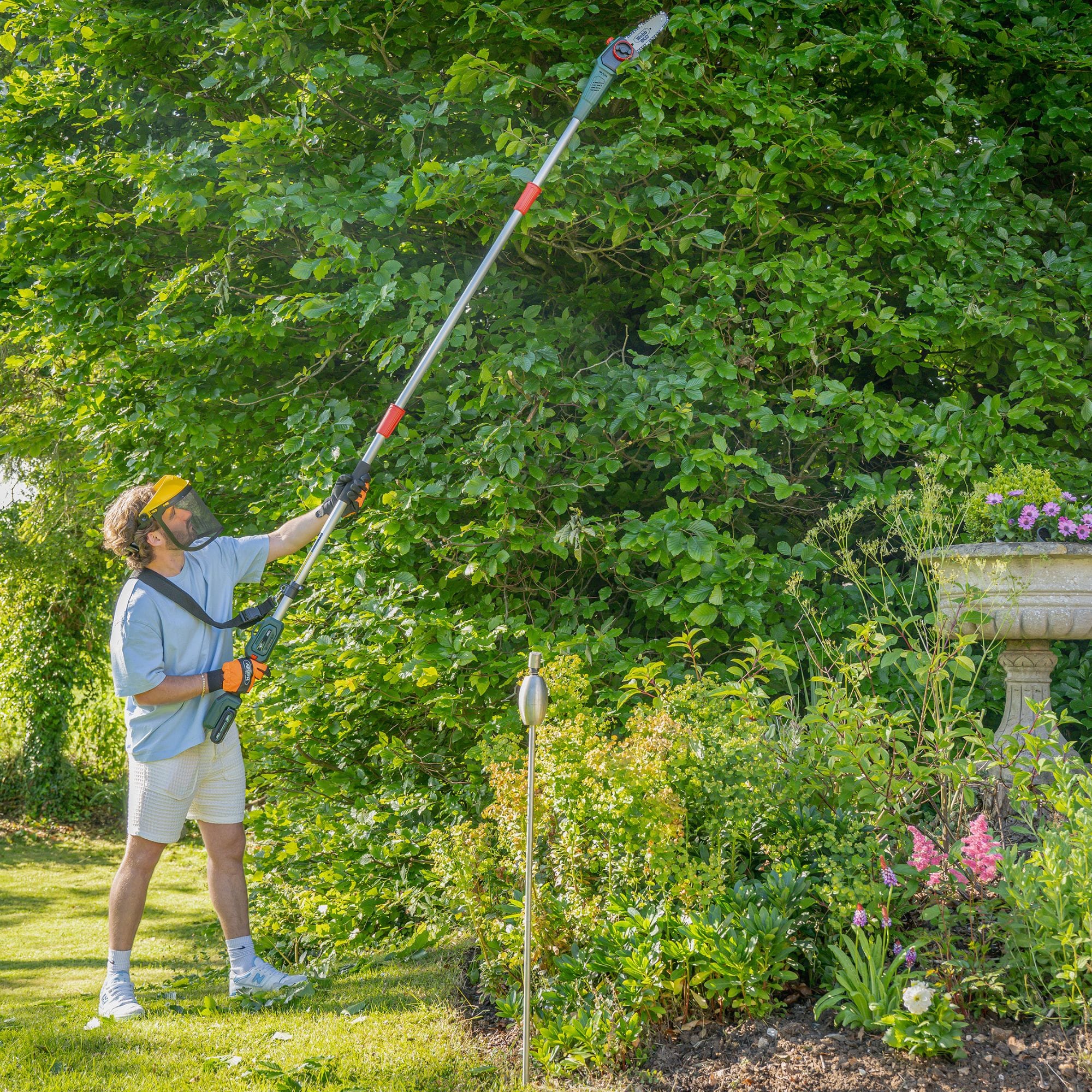 olyf2jl34sa.jpg - Mowers Online Man using pole pruner on hedge