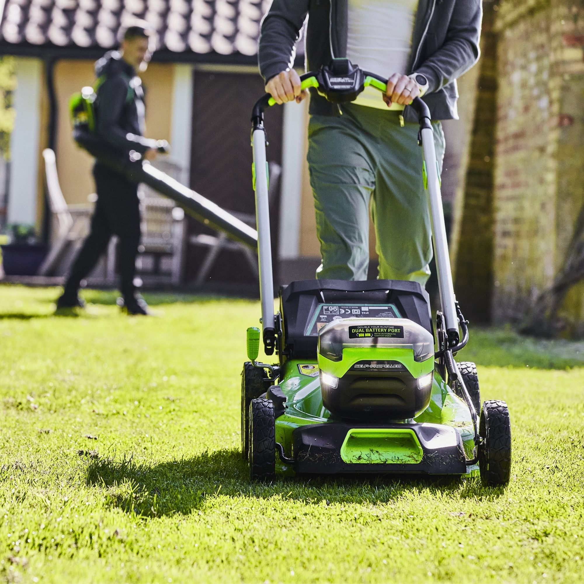 ul2k40e2pnw.jpg - Mowers Online Person using green and black cordless lawn mower