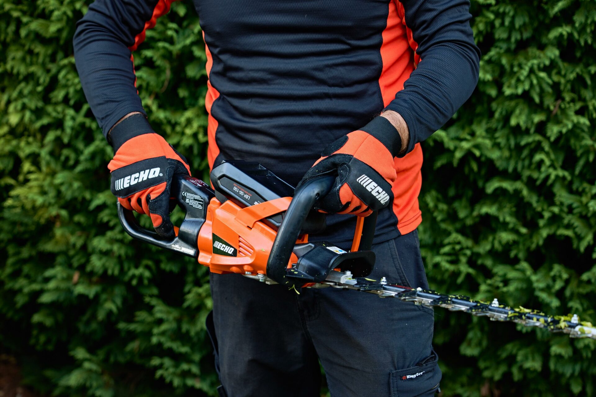wacpbbvq4st.jpg - Mowers Online Person holding hedge trimmer with orange accents