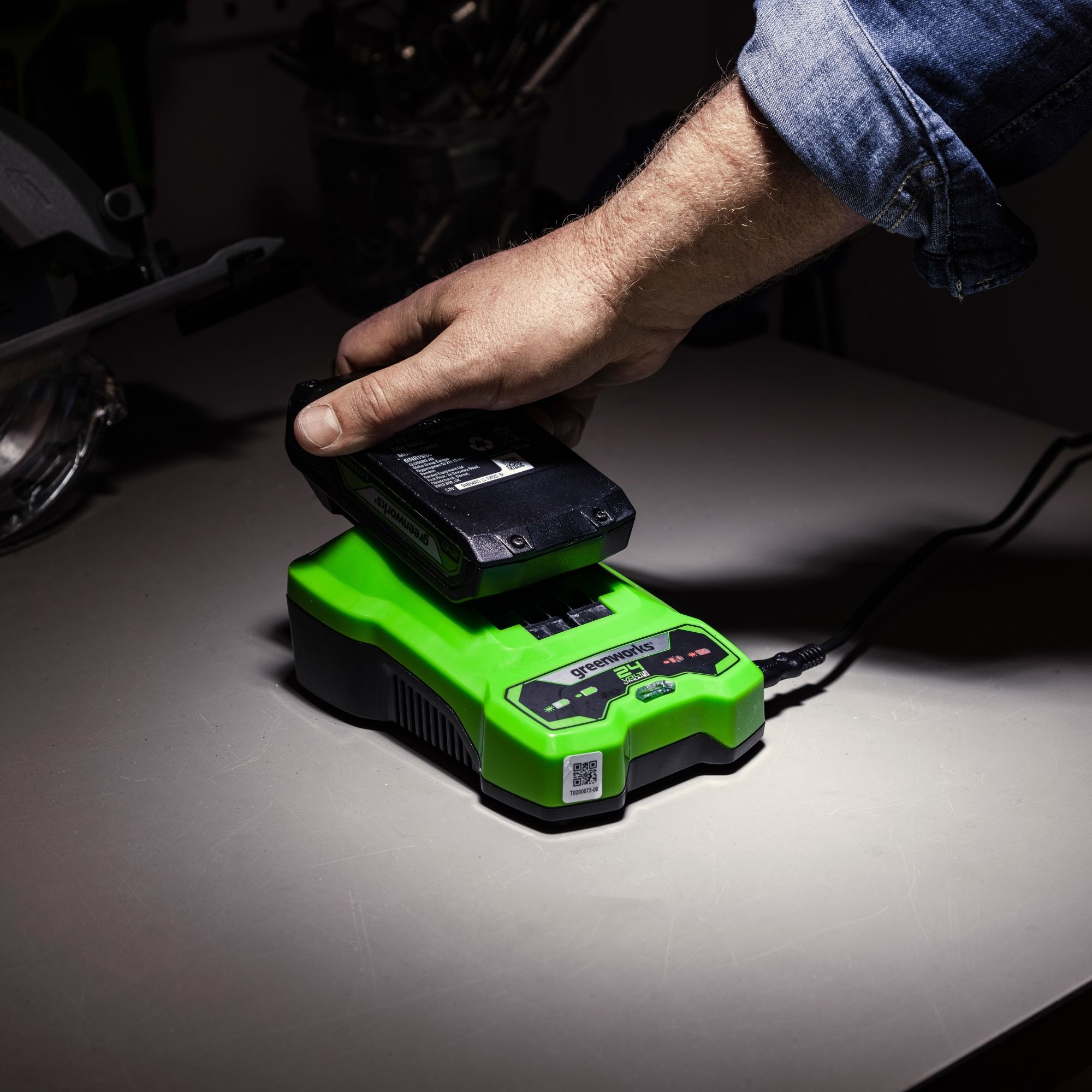 wg2g101lh5y.jpg - Mowers Online Person placing battery into green power tool charger