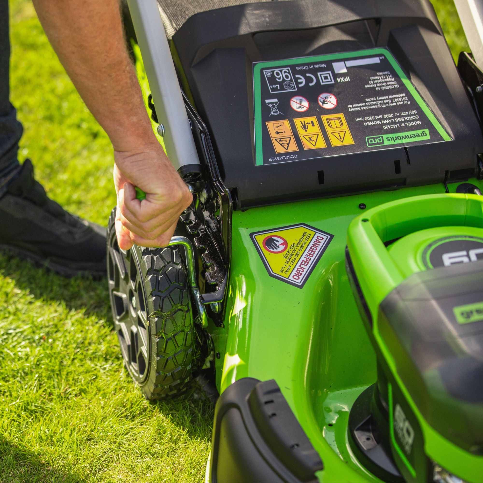 wnkmwsray5y.jpg - Mowers Online Person operating green lawn mower on grass