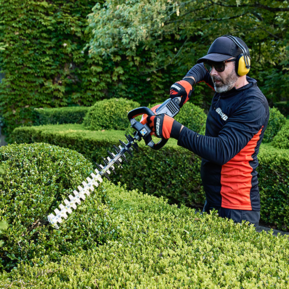 xojplgwge2g.png - Mowers Online Man using electric hedge trimmer on shrub